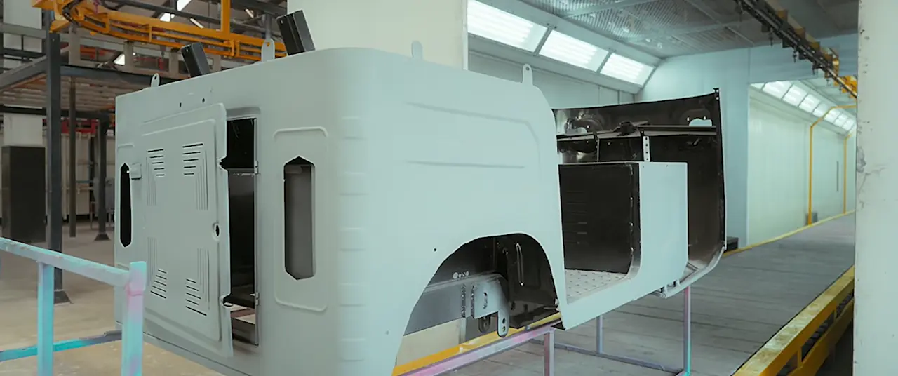 A vehicle cab being spray-painted turquoise inside Mercury’s enclosed paint booth.